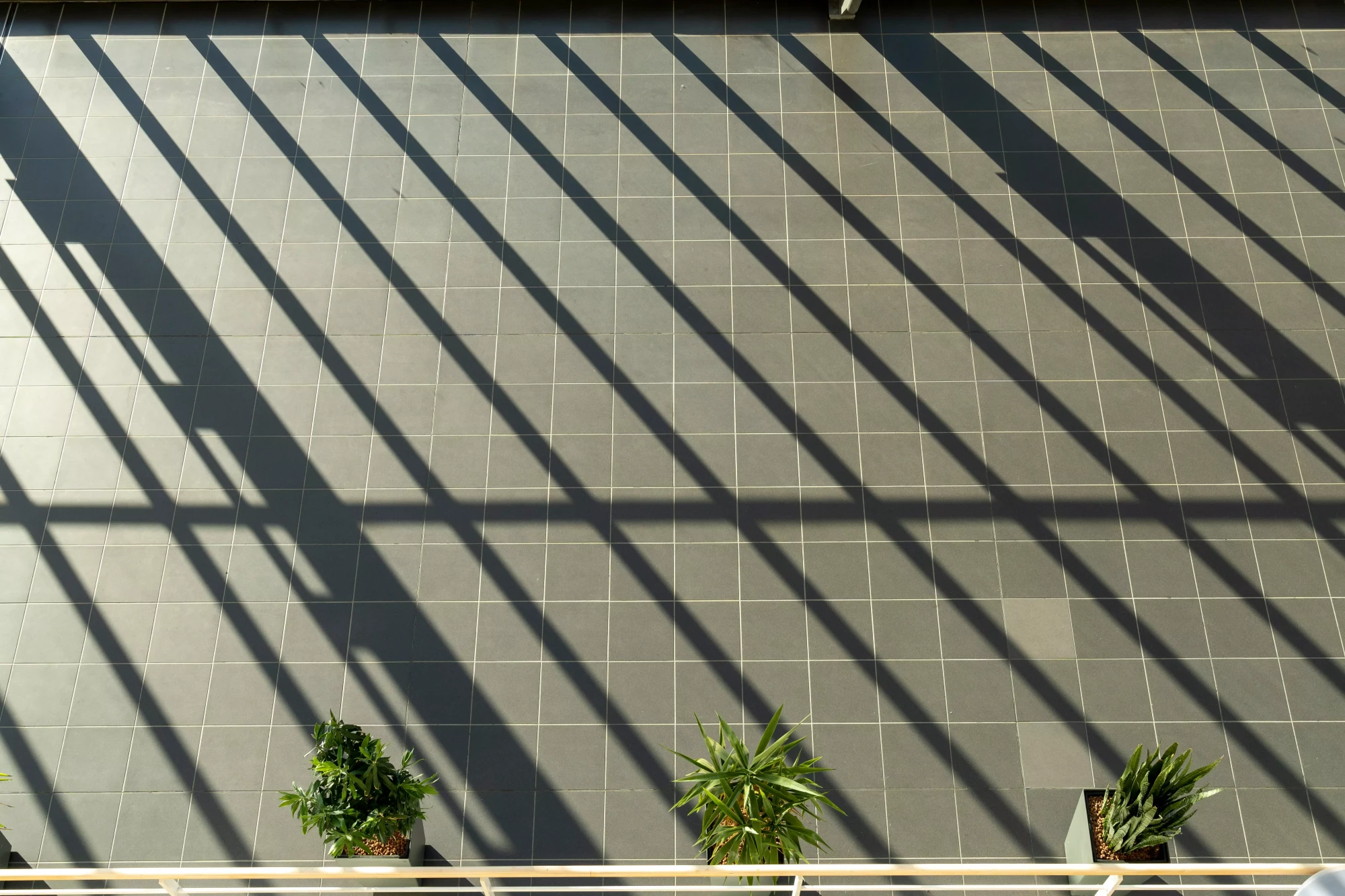 Modern residential roof with clean zinc gutters and dark grey tiles under sunlight